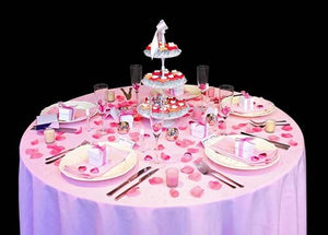 Pink table linens on a round table with plates and a dessert tower centerpiece
