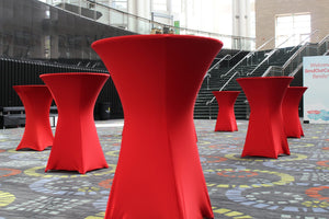 Red Spandex tablecloths set up throughout an indoor convention center