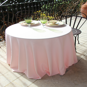 Poly premier white linens on a round table on an outdoor lunch setting