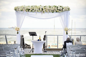  White Spandex table cover on a wedding ceremony stage table outdoors by the beach