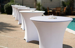 A row of Spandex cocktail table covers in white outdoors by a pool