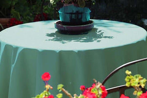 Fine linens on outdoor table with flower pot on top