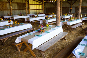 High-end table linens in a barn style reception with sun flowers and wooden centerpieces