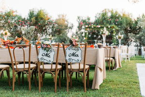 Ivory tablecloths on tables for an outdoor wedding reception with Mr. and Mrs.signs