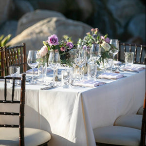 Outdoor reception with white wedding linens and napkins featuring colorful flowers