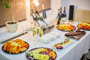 White linens on a reception table with fruit and wine