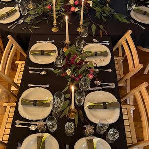 Black table linens with table plates and flowers on top shot from above