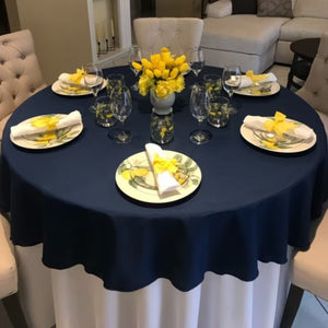 Layered High-end Polyester linens in white & navy at a classy family dinner table with yellow tulips