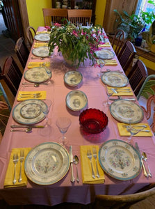 Pink tablecloth on a large dining room table with china and glasses