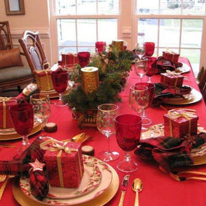 Holiday red linens on Christmas table with place settings and decorations