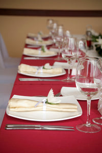 Exquisite Red tablecloths on rectangular tables with places and ivory napkins. 