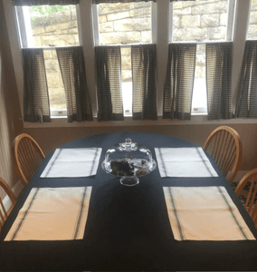Black oval cotton tablecloth with white placemats 