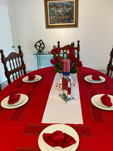 A Cotton tablecloth on an oval home table with napkins folded into roses and roses on the table
