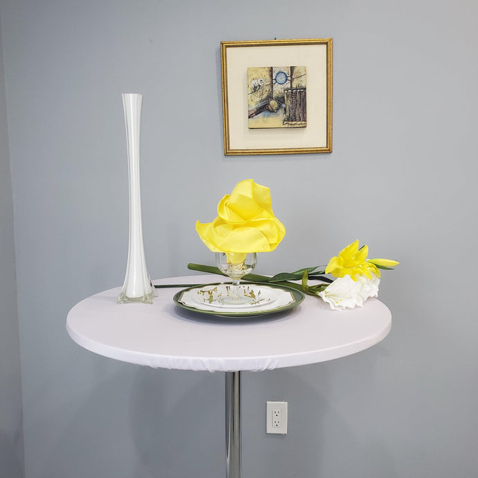 White round table topper on a cocktail table with yellow flowers and yellow napkin