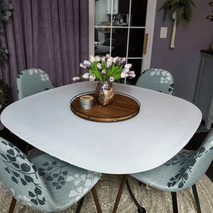 White round fitted tablecloth on a  round table with purple tulips.