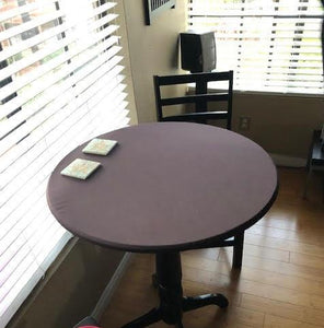 Chocolate fitted tablecloth round table by window in a home
