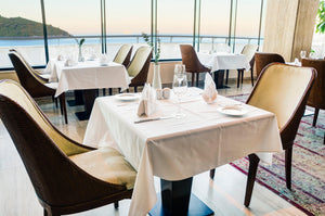Square white table linens in an ocean view restaurant by the water
