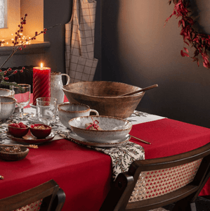 Red table linens in an intimate Christmas dining setting with a red candle and plates