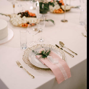White wedding table linens with a pink napkin on a plate in an elegant reception setting 