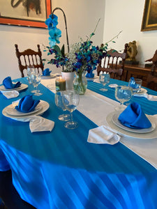 Blue oval tablecloth with cloth napkins and a white table runner