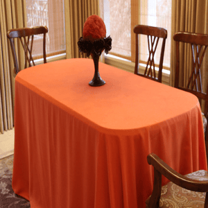 Orange table cloth on a small dining table in a home setting with wooden chairs