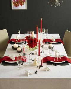 Formal tablecloth in a holiday table setting with Red napkins and ornaments 