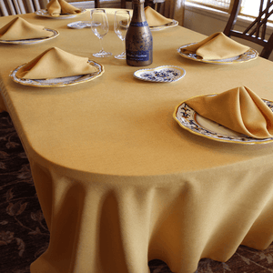 Dinner linens in gold color with matching napkins and a champagne bottle