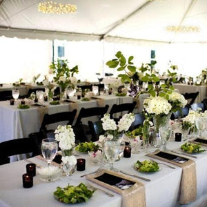 Wedding table linens at a Lavish outdoor reception under a tent with flowers, candles and silverware