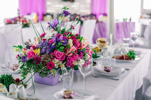 Wedding linens in white on rectangular tables with colorful flower centerpieces