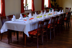  white formal table linens in a banquet restaurant setting with standing napkins by windows