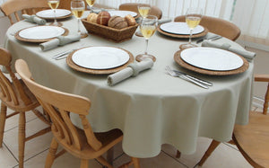 Tan oval Table linens on a dining room table with matching napkins, plates, and bread for the table