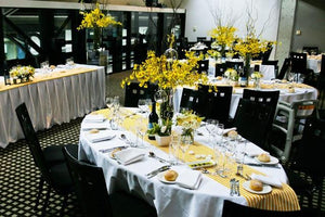 White Spun table linens on oval tables with yellow runners in an upscale banquet style restaurant