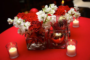 Holiday Red colored tablecloth with white candles and a festive centerpiece