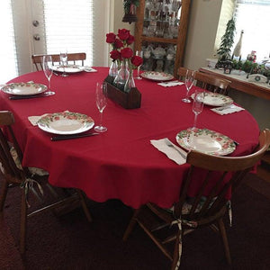 Red Spun table linens on an oval table with roses and champagne glasses