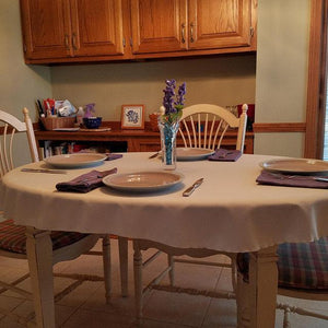 Tan colored table linen on an oval table in a home kitchen with lavender flowers