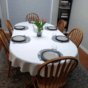 White oval table cloth with placemats and a vase of tulips 
