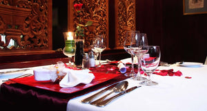 Square restaurant tables with white twill linens and a red table runner at a fine restaurant