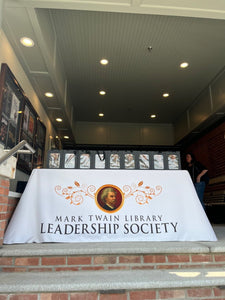 Table with a 'Mark Twain Library Leadership Society' tablecloth in an indoor setting.