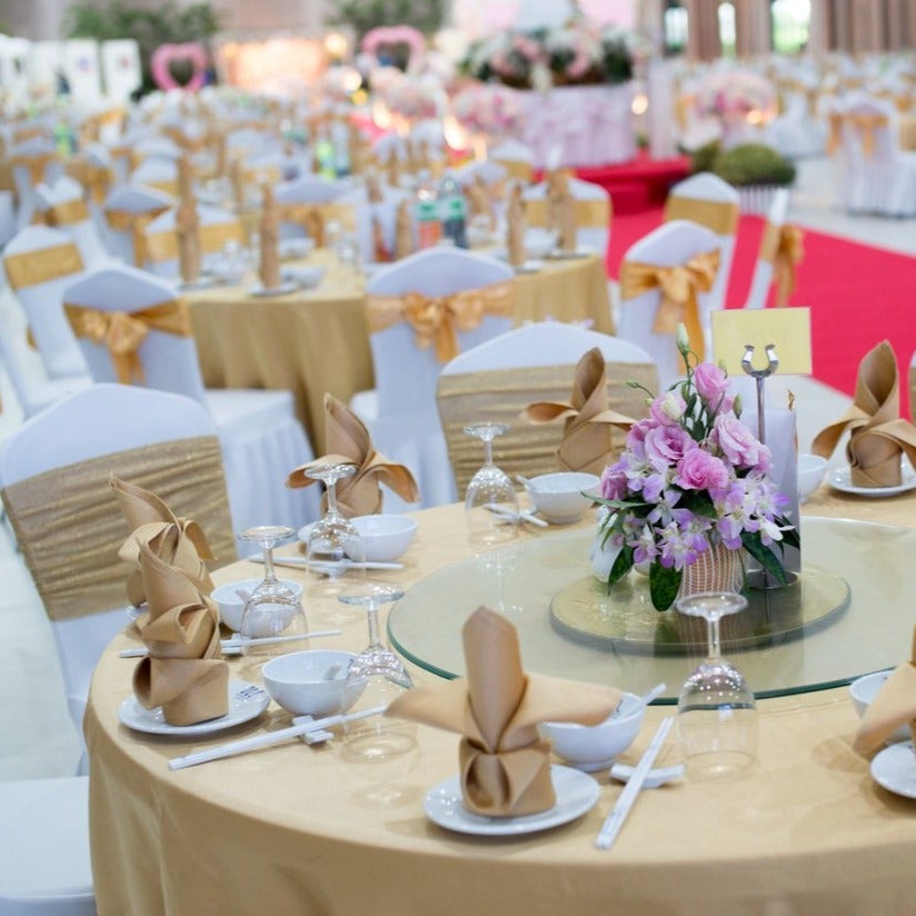 Banquet linens on many round tables with golden chair ties