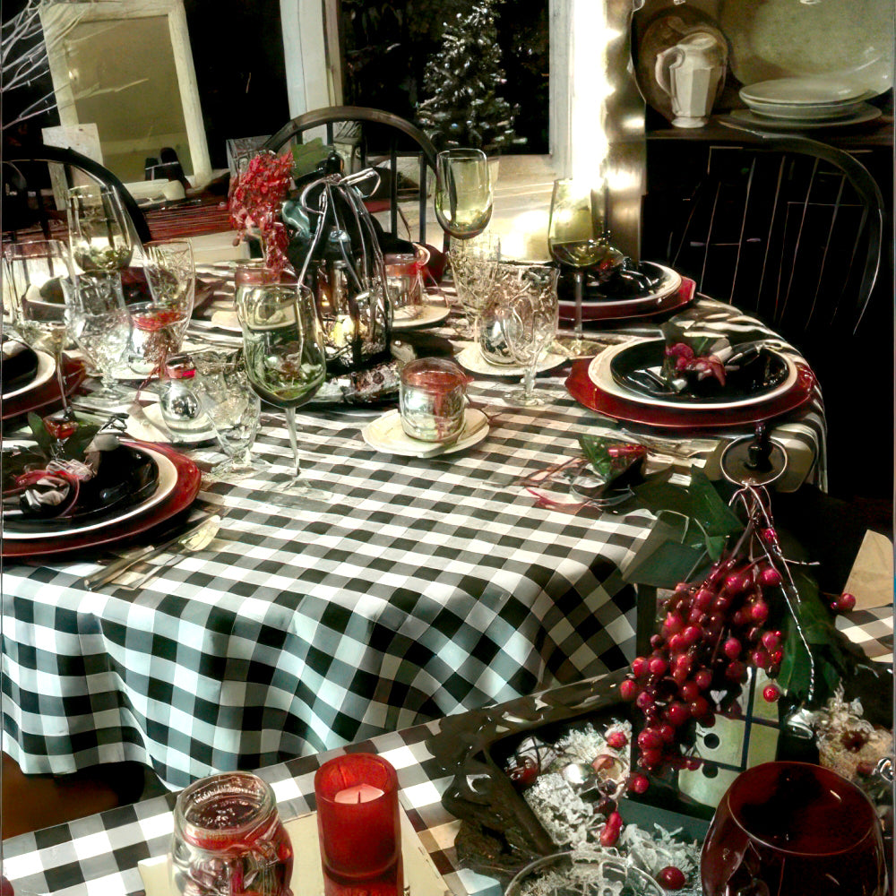 Decorative Christmas table setting with checkered tablecloth, candles, and festive decor.