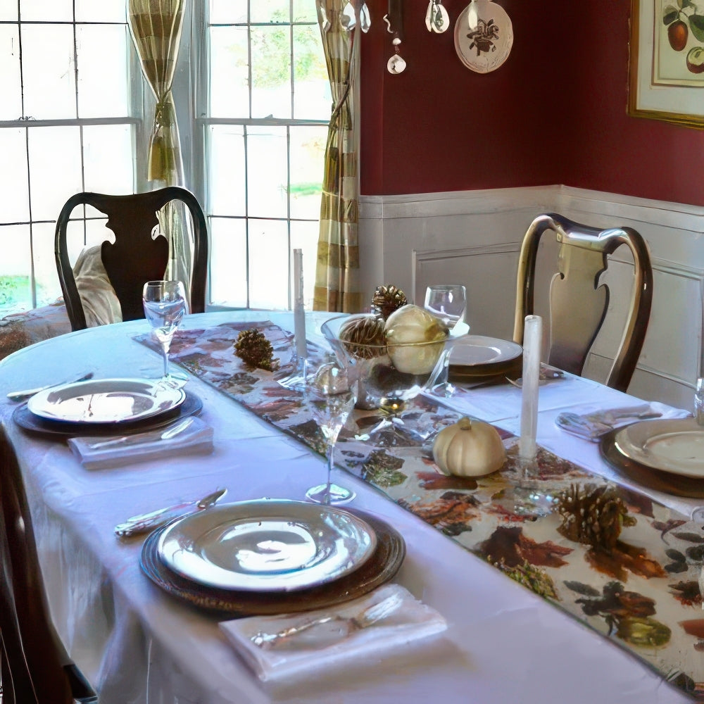 Dining table set for a meal with fall-themed decor, including pumpkins and leaves on a tablecloth.