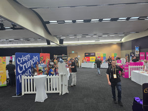 Attendees at a food convention. Lots of vendor banners and each table has a white blank tablecloth