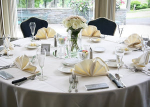 White wedding linens on a round table with clam shaped napkins