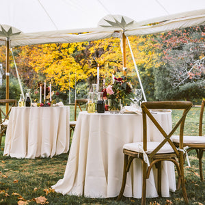 Round Havana tablecloths in ivory under a tent at an outdoor reception