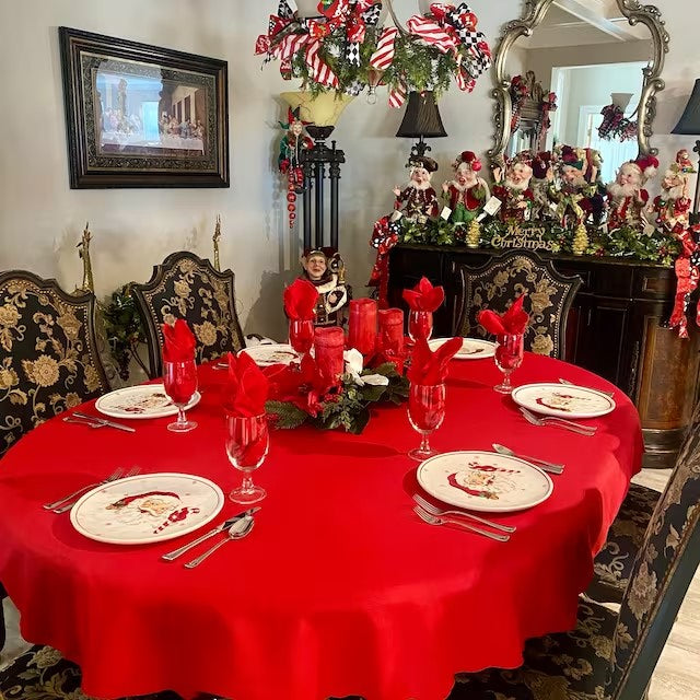 Christmas table linen on an oval table with Santa Claus Plates and red napkins