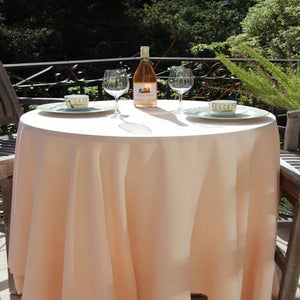 Ice peach colored linens on a round table with a wine bottle and glasses