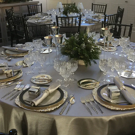 Silver Majestic tablecloth on round tables during the holidays. Beautiful Christmas tablecloth setting