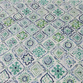 wipe clean oval tablecloth with green and blue geometric design on a white background.