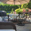 Oilcloth tablecloth with lemon prints on an outdoor table with umbrella.