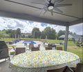 Waterproof wipe clean oval tablecloth with bright lemons and vines on an outdoor deck overlooking a pool